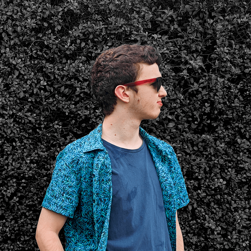 Image of a young man with red sunglasses standing in front of a black and white image of bushes.